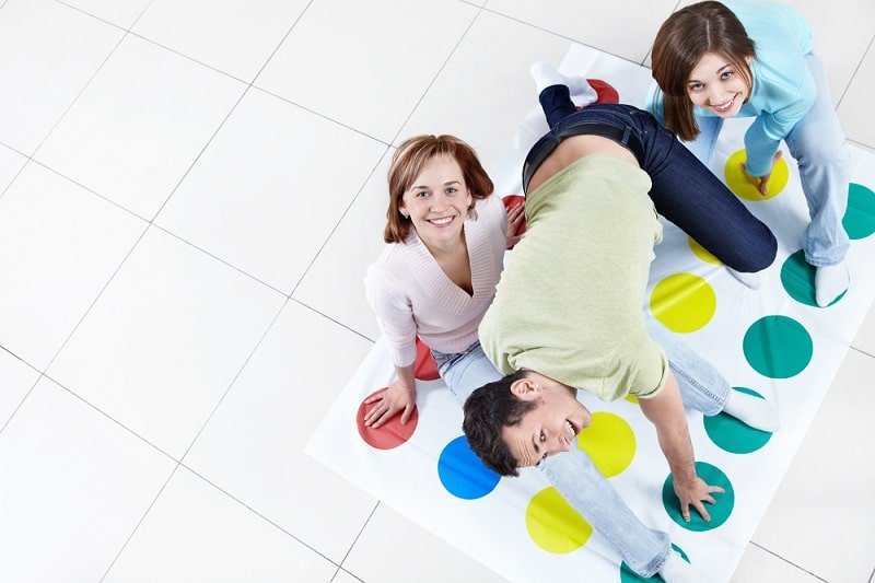 Drei Leute spielen Twister im Wohnzimmer