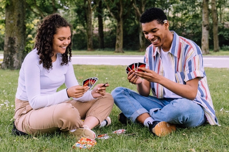 Mann und Frau sitzen auf Gras Spielkarten