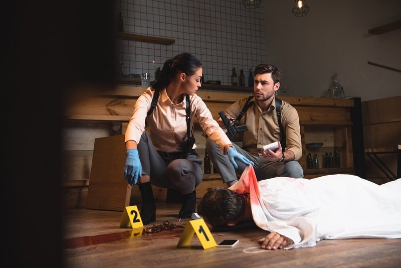 Weibliche und männliche Detektive sammeln Beweise und untersuchen Leichen am Tatort
