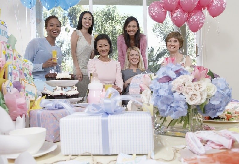 Alles über Babyparty: Spiele, Organisation & Geschenke Frauen sitzen an der Babyparty hinter einem Tisch der Geschenke