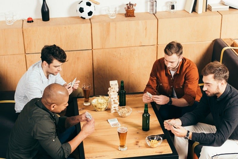 Männer spielen Karten während sie Zeit zusammen im Café verbringen