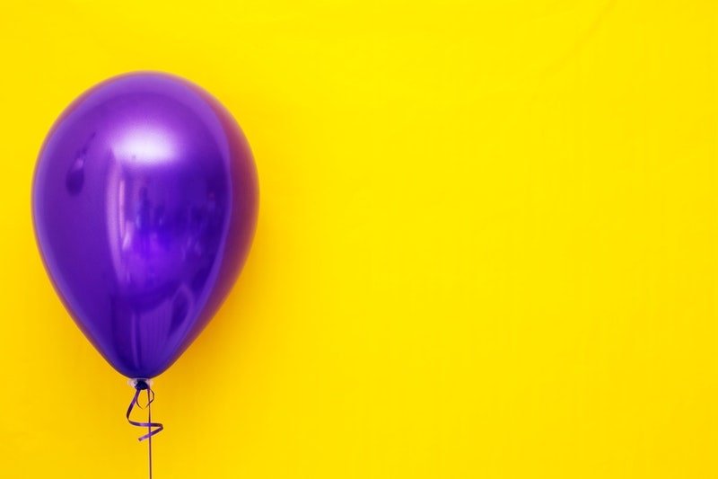 lila Ballon gegen gelben Hintergrund
