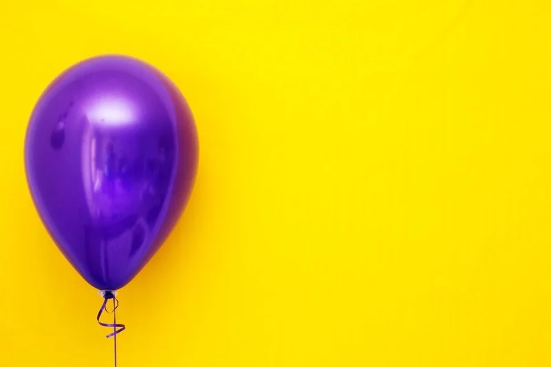 lila Ballon gegen gelben Hintergrund