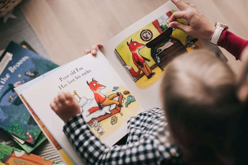 Eltern halten Kind und lesen ein Buch