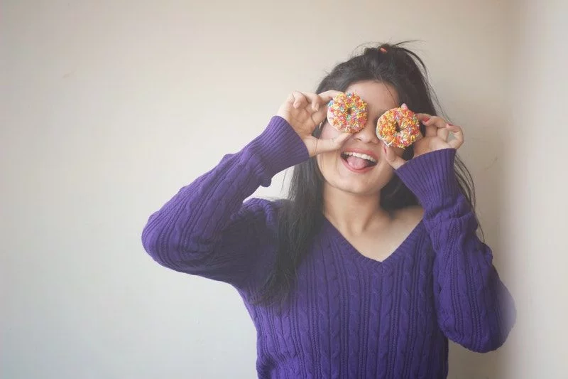 Frau bedeckt ihre Augen mit Donuts