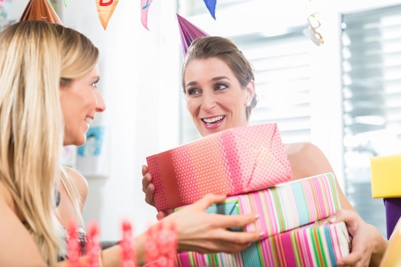 15 Ideen für die Geschenke zum ersten Geburtstag Frau hält Geschenkboxen