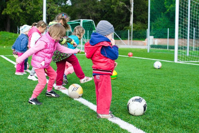 Gruppe von kleinen Kindern, die mit Bällen auf einem Feld spielen