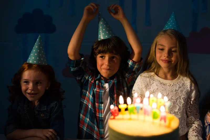Kinder hinter einer Geburtstagstorte mit Kerzen