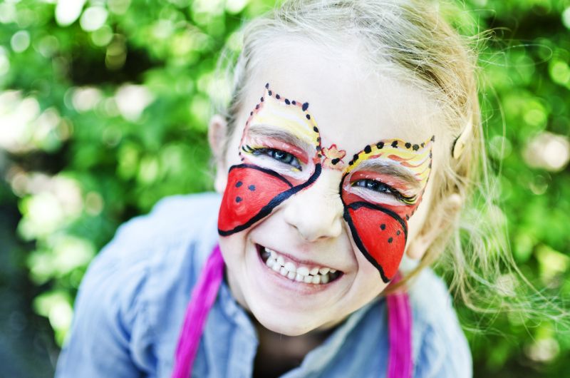 Mädchen mit einem Schmetterling über ganzem Gesicht gemalt