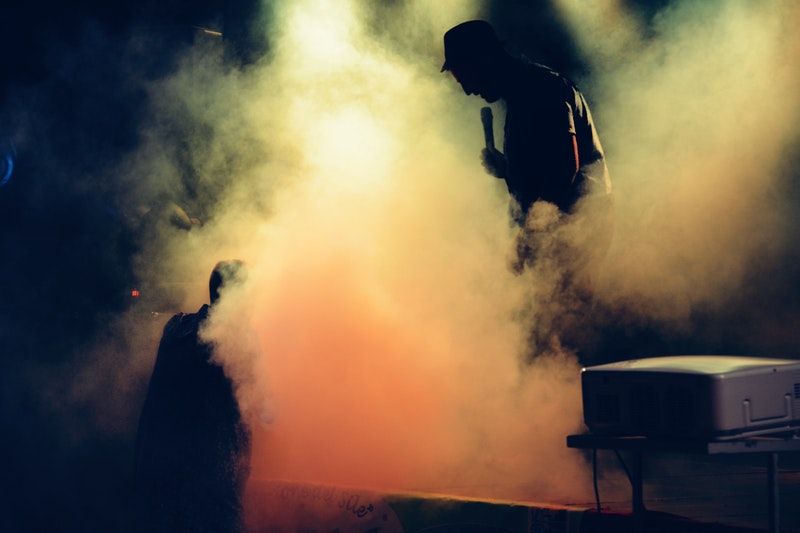 Alles über Nebelmaschine - Fluide, Fogger, Hazer & Faze Mann hält Mikrofon auf der Bühne voller Nebel