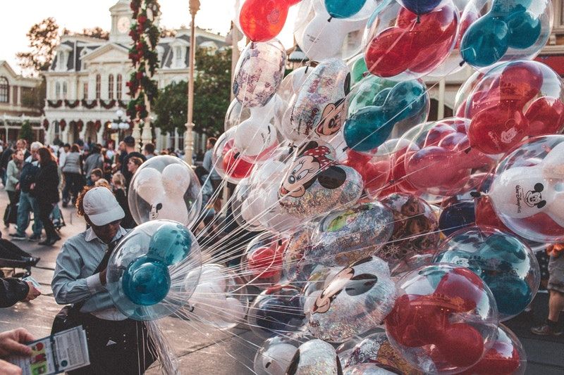 Luftballons - Alles Rund um die Ballons Mann hält Dutzend verschiedener Luftballons auf der Straße