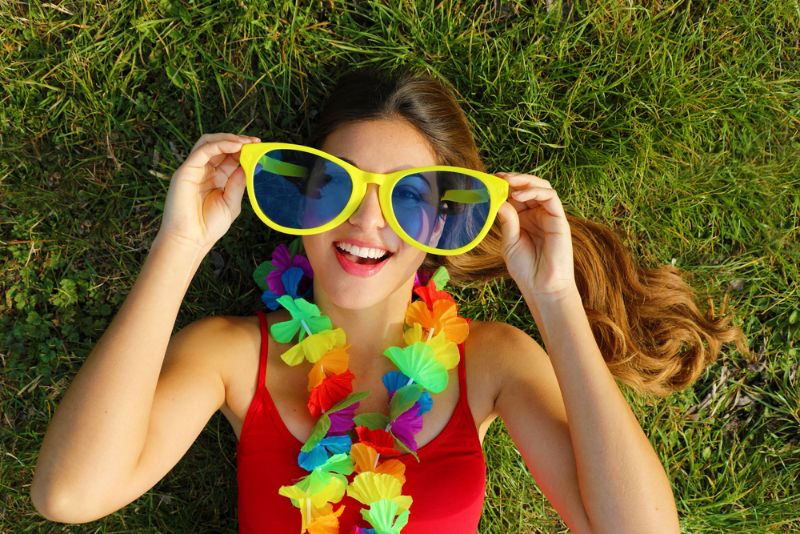 Tipps & Tricks und 5 Rezepten für die beste Cocktail Party Mädchen mit großer Sonnenbrille und Blumenhalskette, die auf dem Gras liegt