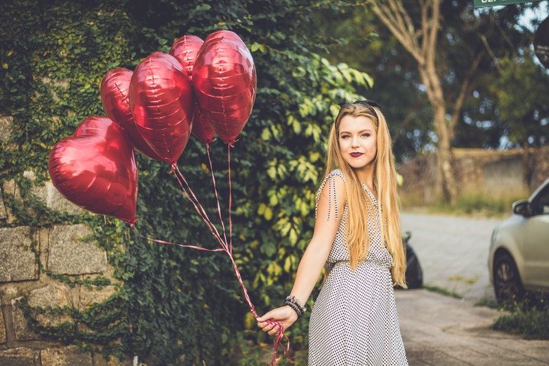 Luftballons - Alles Rund um die Ballons blondes Mädchen, das draußen rote herzförmige Luftballons hält
