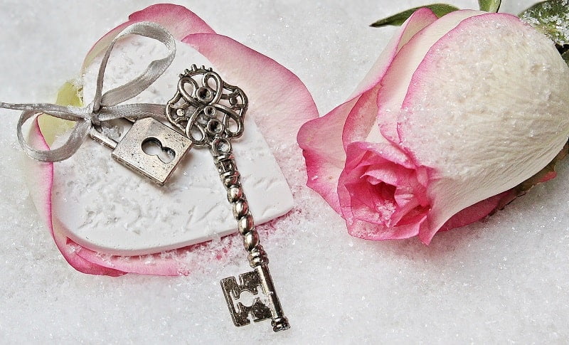 Escape Room Für Kinder - Mottoparty und Schatzsuche in Einem alter Schlüssel auf weißem Papier mit rosa Rose