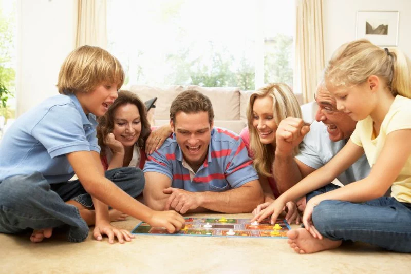 Familie sitzt auf dem Boden und spielt Brettspiele
