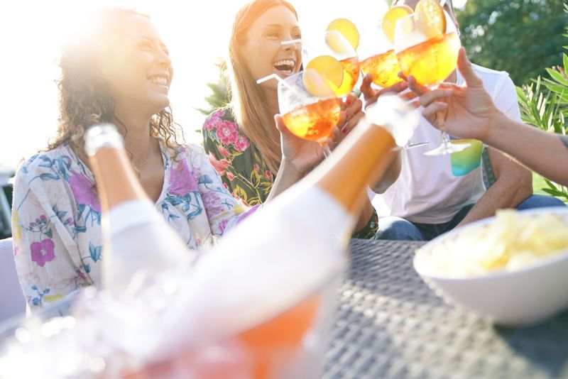 Organisieren Sie die perfekte Beachparty Freunde stoßen an mit Sommercocktails