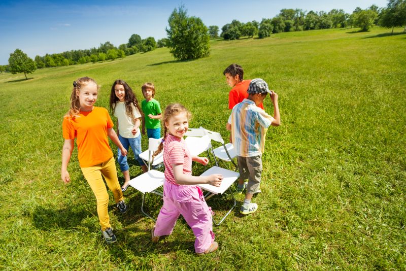 Kinder spielen draußen mit Stühlen