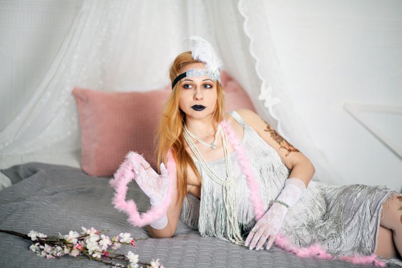 Gatsby Party Die Goldenen Zwanziger Mädchen gekleidet in Vintage-Kleid auf dem Bett liegend