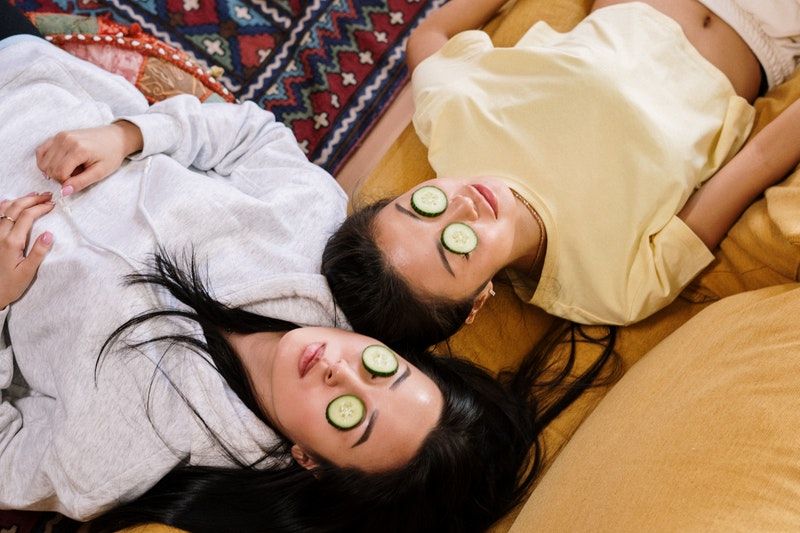 Ideen für Deine Perfekte Pyjama Party zwei Mädchen, die mit Gurken im Gesicht auf der Couch liegen