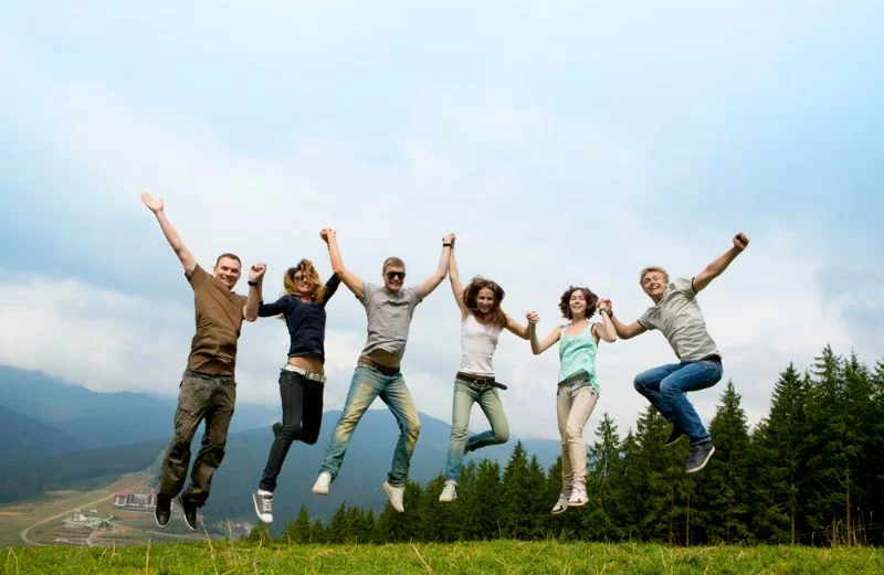 Sechs Freunde springen auf einem Berg in die Luft