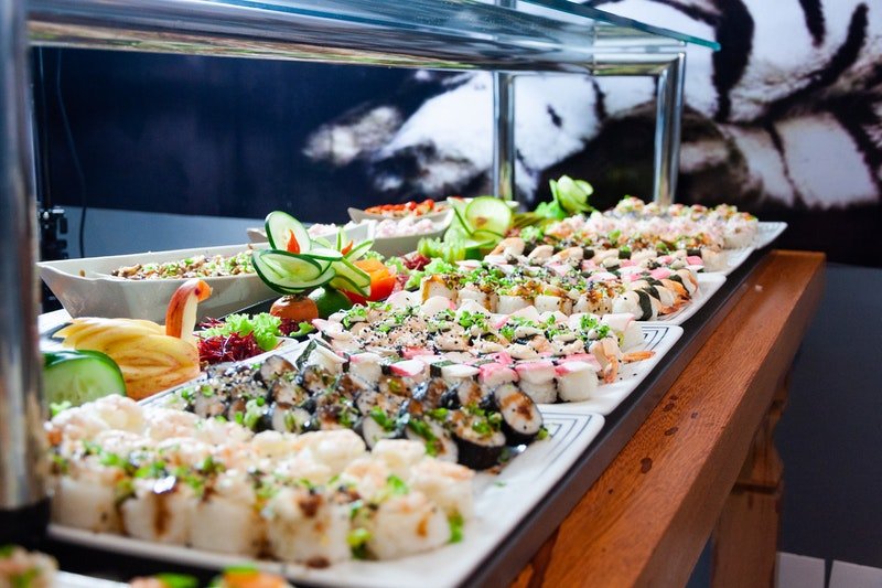 Gatsby Party Die Goldenen Zwanziger Sushi auf weißen Tellern und braunem Holztisch