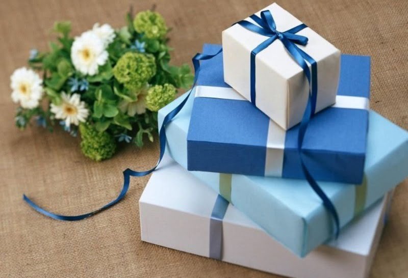 Vier-Geschenkspakete-mit-Blauen-Schleifen-im-Hintergrunt-mit-Blumen
