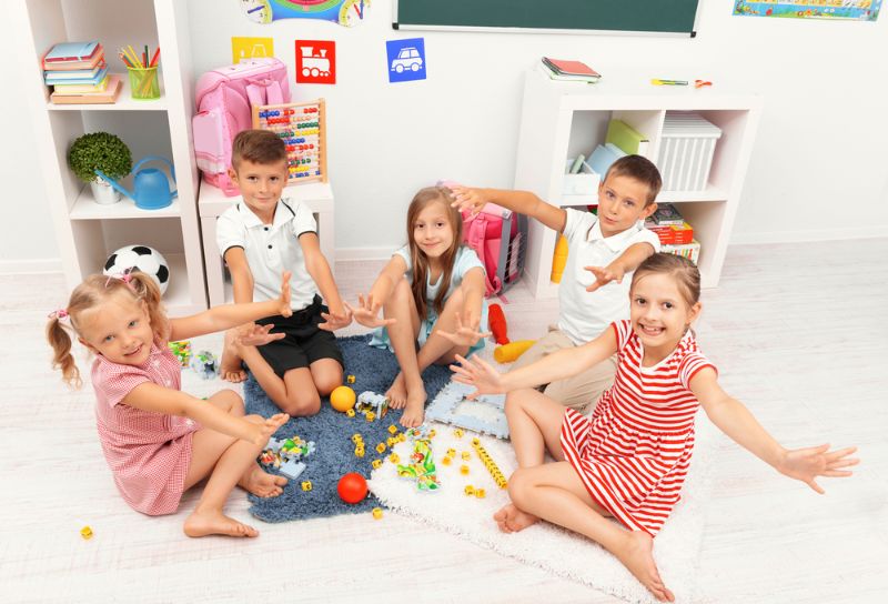 fünf Kinder sitzen auf dem Boden und spielen