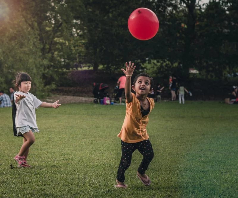 zwei Kinder laufen und spielen mit Ballon