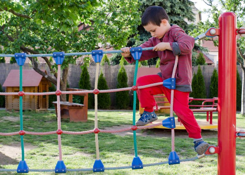 Ein-Junge-in-einem-roten-Outfit-mit-blauen-Schuhen-spielt-auf-dem-Spielplatz