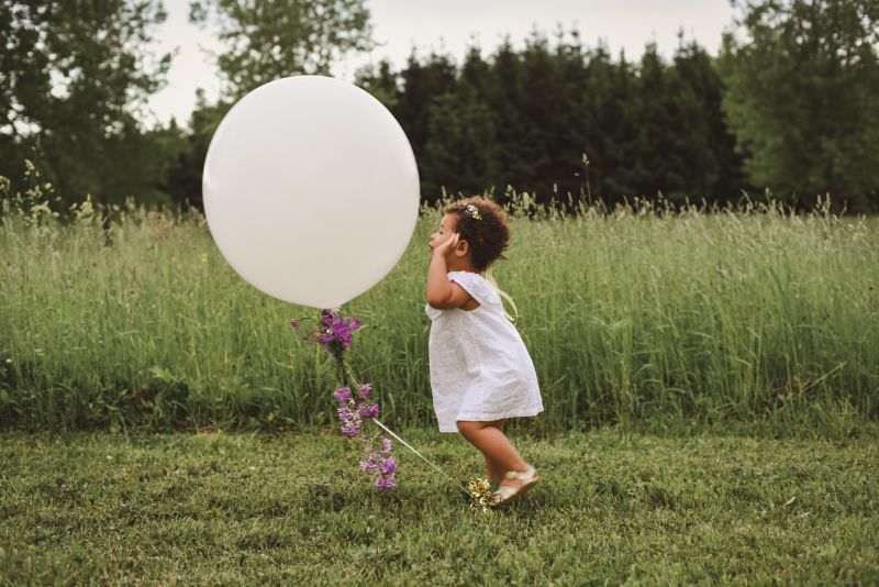 Ein-kleines-Mädchen-in-einem-weißen-Kleid-spielt-mit-einem-großen-weißen-Ballon-1-min