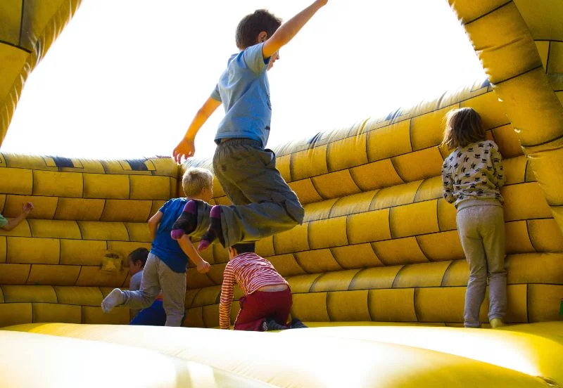 Eine-Gruppe-von-Kindern-die-in-eine-gelbe-Trampolinburg-springen