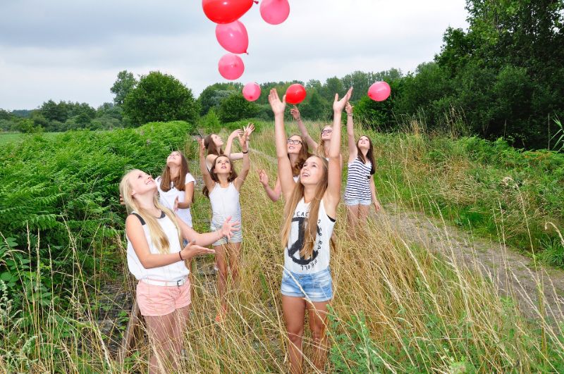 Eine-Gruppe-von-Mädchen-spielt-mit-roten-und-rosa-Luftballons-im-Freien-1-min