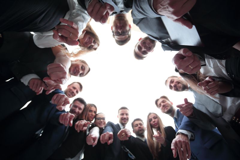 Konzept der Teambildung Das Geschäftsteam bildet einen Kreis und zeigt auf die Kamera