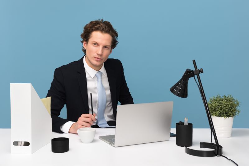 Mann-mit-Geschäftsblick-sitzt-neben-Laptop-Computer-und-Teetasse