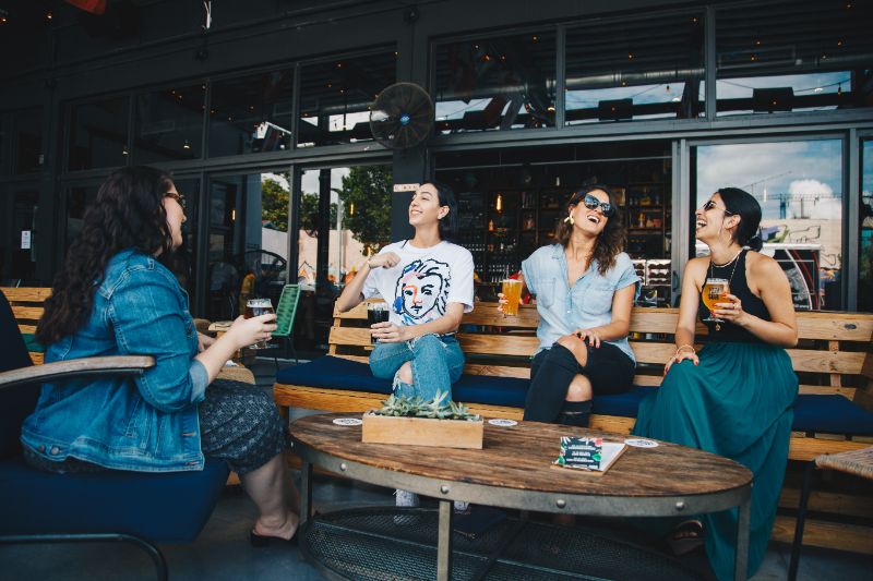 150 Freche Sprüche: Ein Bisschen Fies Aber Lustig Frauen die viel lachen und auf einer Holzbank sitzen