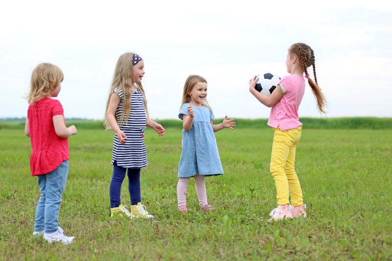 Vier-kleine-Kinder-die-draußen-mit-einem-Fußball-spielen-das-Spiel-Verrate-mir-deinen-Namen