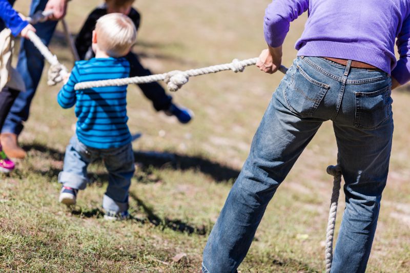 Zwei Familien die altes Seilziehspiel im Park spielen
