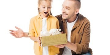 Vater-gibt-einer-geschockten-Tochter-ein-verpacktes-Geschenk