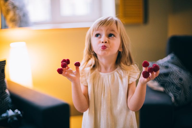 verträumtes-Mädchen-mit-Beeren-an-den-Fingern-zu-Hause