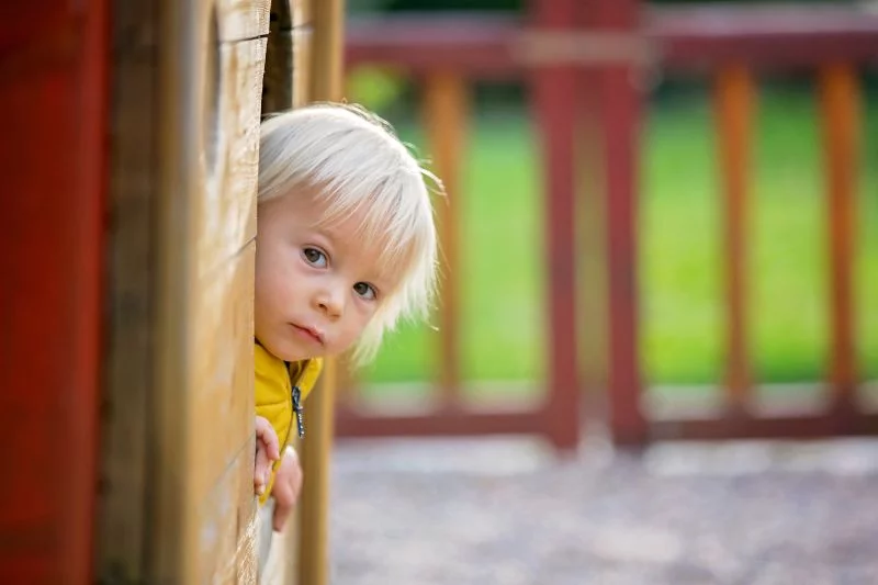 Blondes-kleines-Kleinkindkind-in-gelber-Jacke-das-auf-dem-Spielplatz-spielt