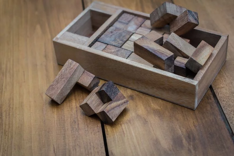 Holzblock-Brain-Teaser-Puzzle-auf-Holz-Hintergrund-ausgebreitet