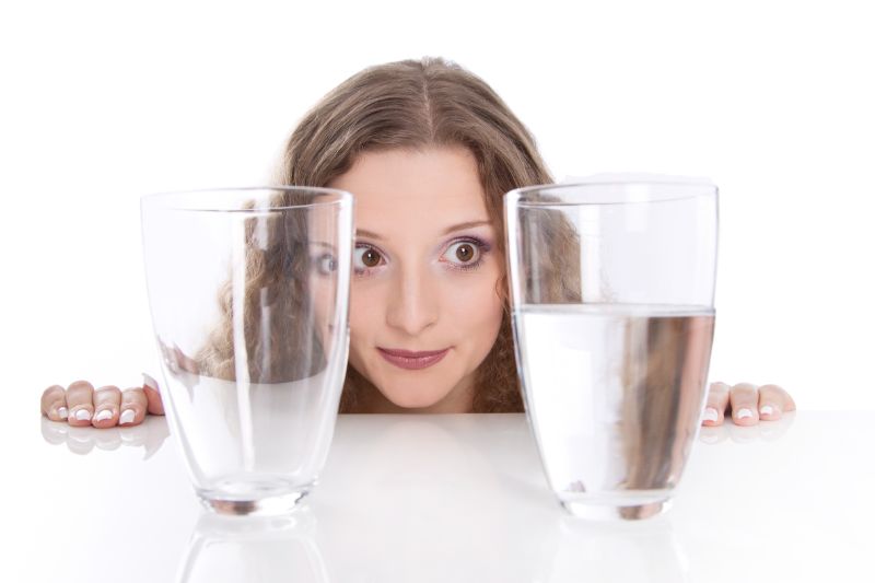 Mädchen-beobachtet-ein-volles-und-ein-leeres-Glas-Wasser