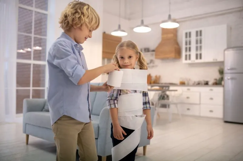 Zwei-Kinder-die-zu-Hause-Toilettenpapier-Mumienspiel-spielen-und-unterhaltet-aussehen