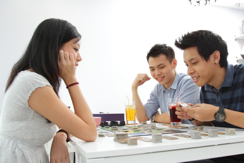 Eine-Gruppe-von-Freunden-die-ein-Brettspiel-in-einem-Cafe-spielen, spiele zu dritt