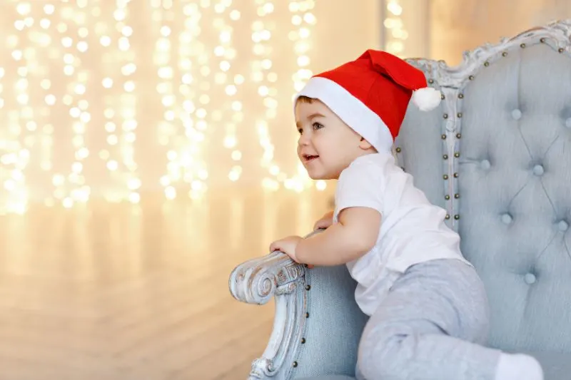 Kleiner-charmanter-Junge-in-roten-Weihnachtsmutzen-die-auf-einem-Stuhl-aga-sitzen