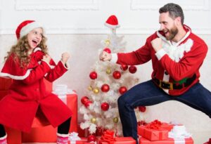 Weihnachtsspiele.-Nettes-Madchen-spielen-mit-Vater-nahe-Weihnachtsbaum.-Verspielte-Tochter-und-Vater-feiern-Weihnachten.-Winteraktivitat-und-Spas.-Kind-geben-vor-fur-Weihnachtsgeschenke-zu-kampfen-1