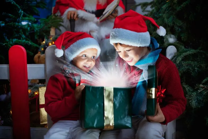 Zwei-Kinder-die-Weihnachtsgeschenk-mit-Lichtstrahlen-offnen