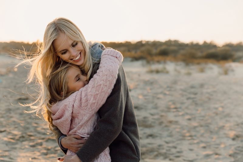 Blonde Frau umarmt ein blondes Mädchen