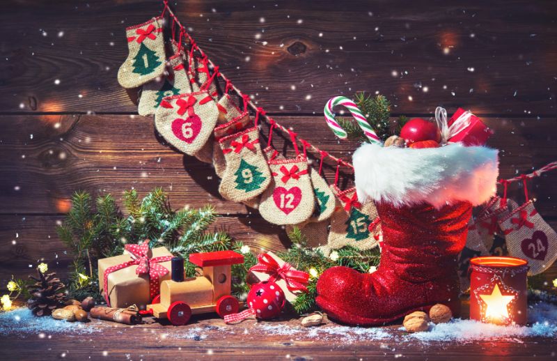 Adventskalender-und-Weihnachtsmannschuh-mit-Geschenken-auf-rustikalem-holzernem-Hintergrund