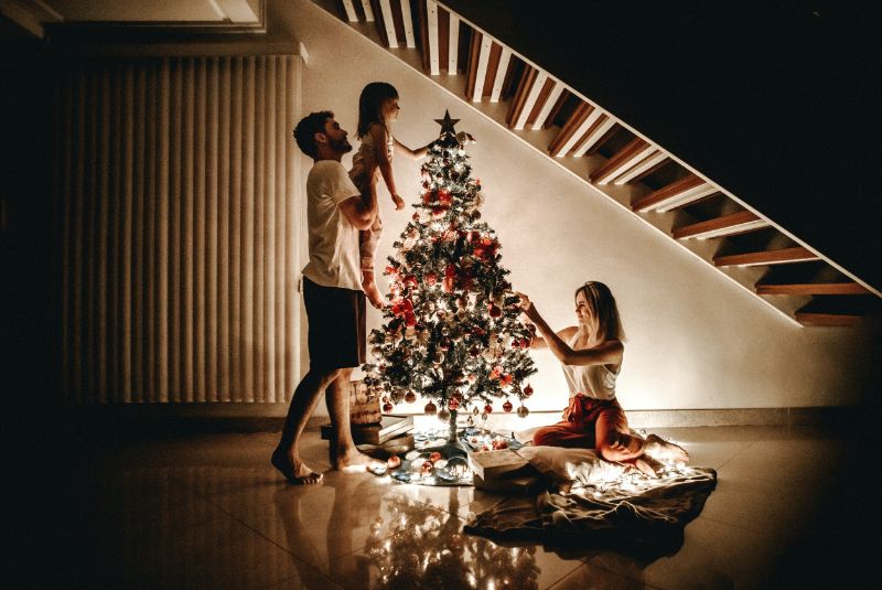 familie-um-einen-weihnachtsbaum-mit-vielen-lichterketten
